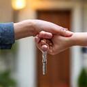Keys being handed over in front of a new home